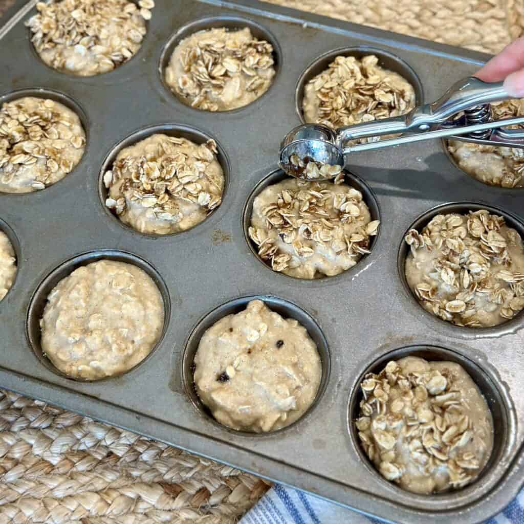 Adding a streusel topping to muffins in a pan.
