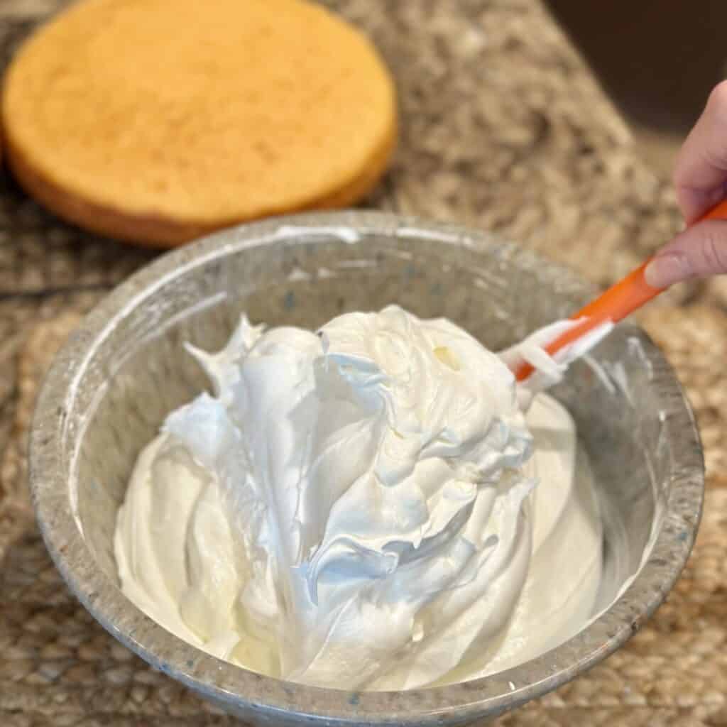 Folding whipped cream in icing ingredients.