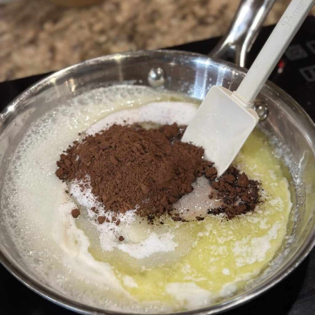 Mixing together butter, cocoa and sugar in a skillet.