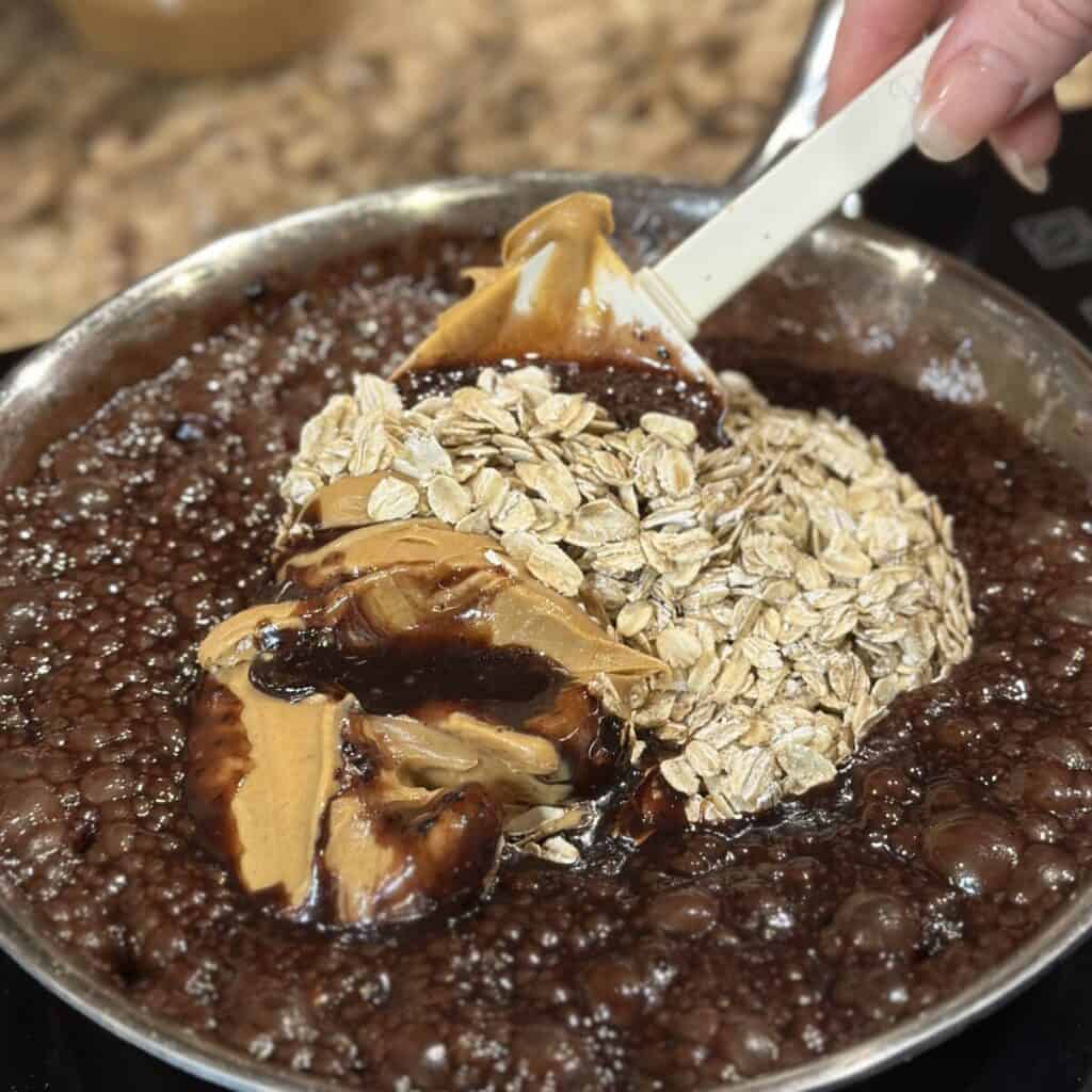 Mixing in peanut butter and oats into cocoa and butter.