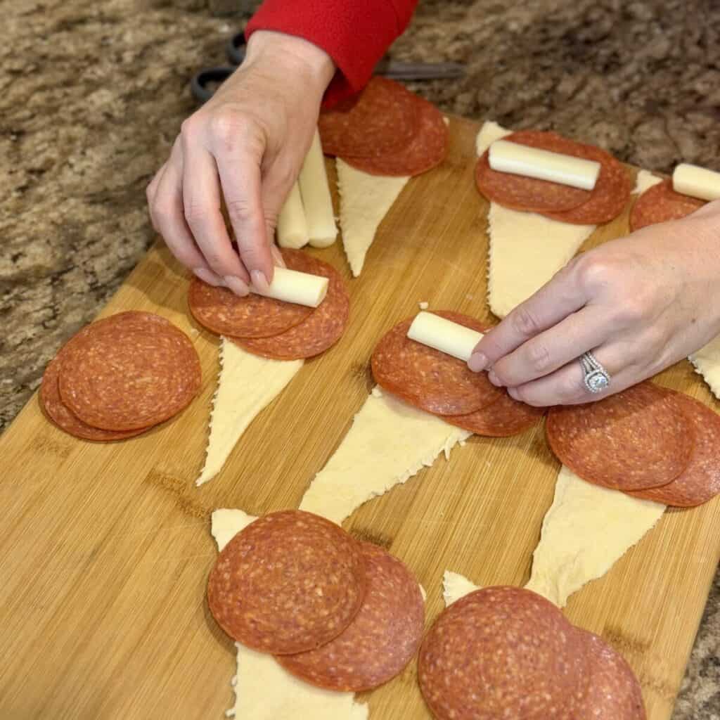 Adding cheese and pepperoni to the top of crescent rolls