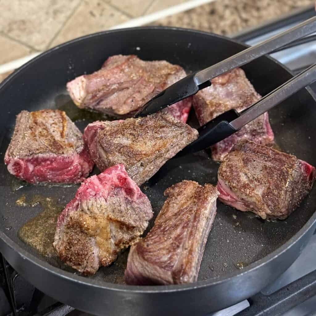 Searing beef short ribs in a skillet.