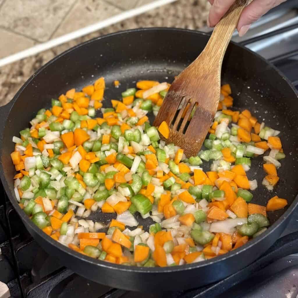 Sautéing mirepoix in a skillet.