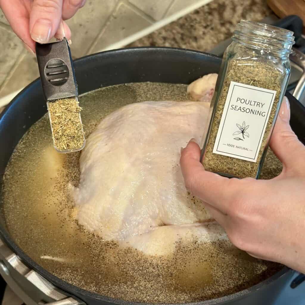 A chicken boiling in broth in a pot.