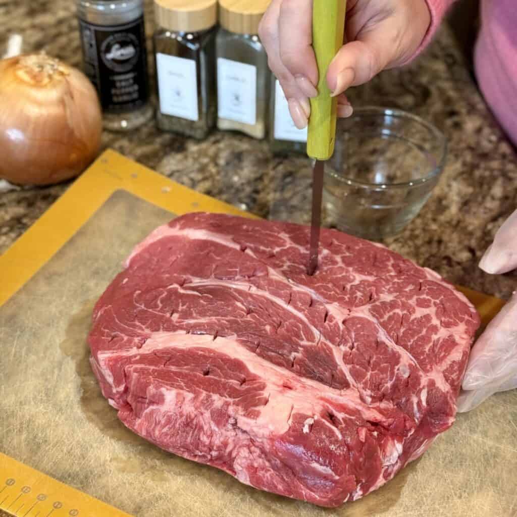 Piercing a roast all over with a knife.