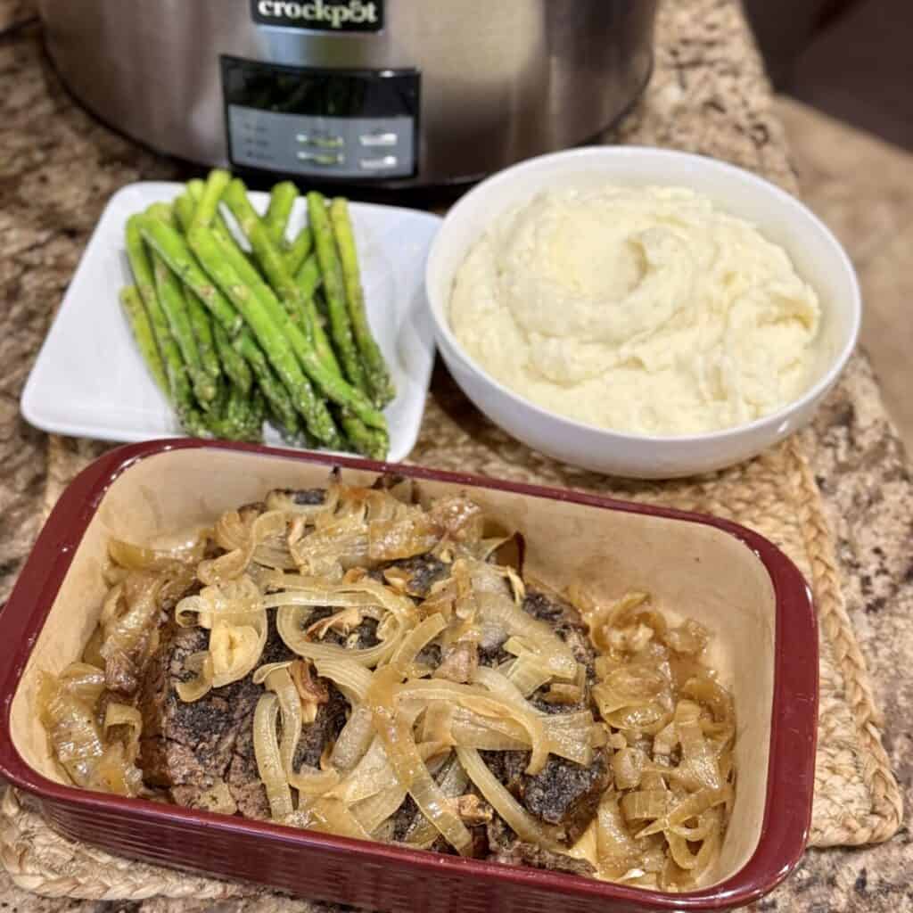 A pan of roast beef, mashed potatoes and asparagus.