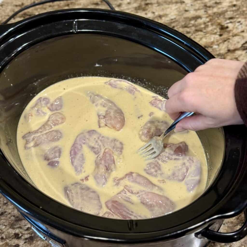 Adding chicken to a crockpot for honey mustard chicken.