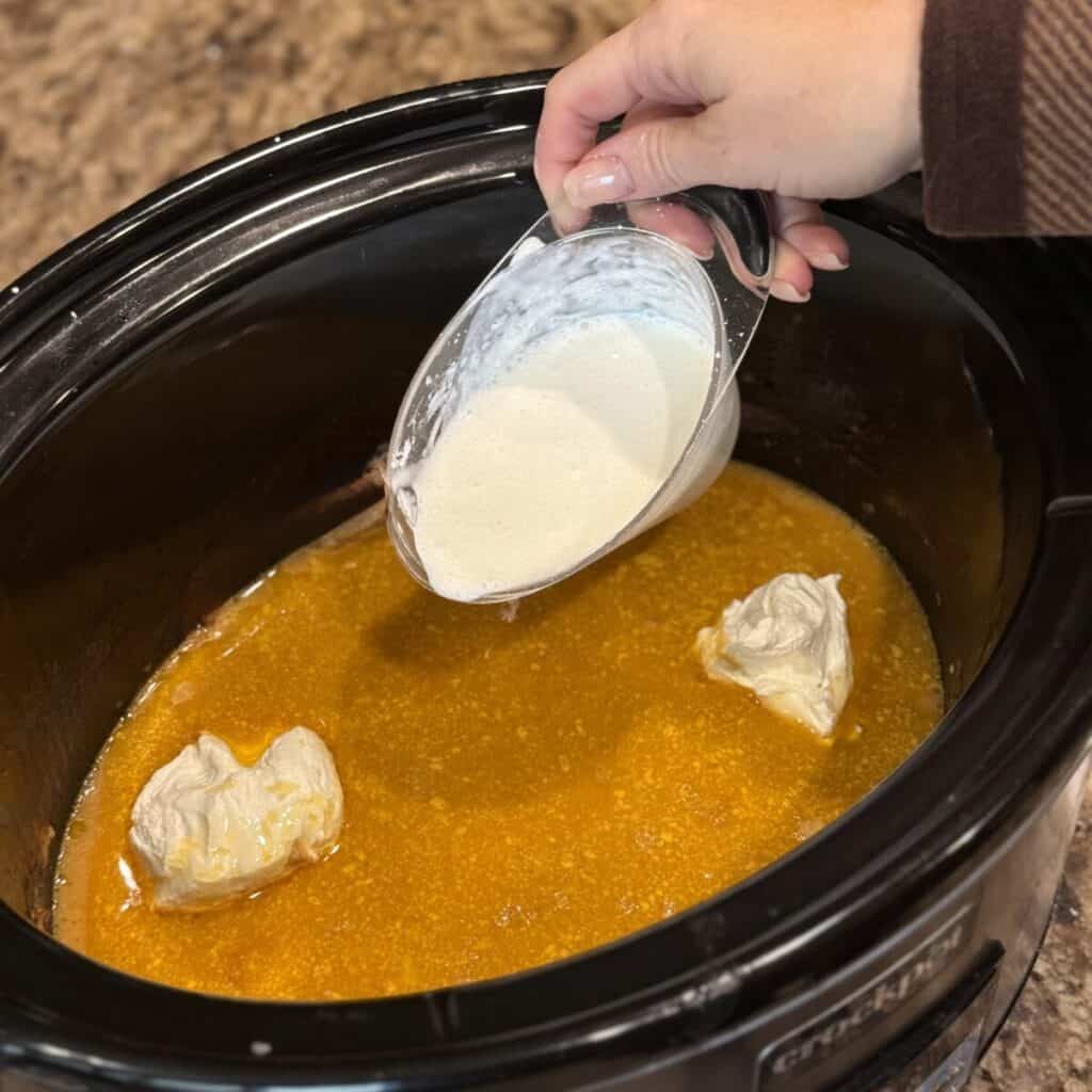 Adding half and half and cream cheese to broth in a crockpot.