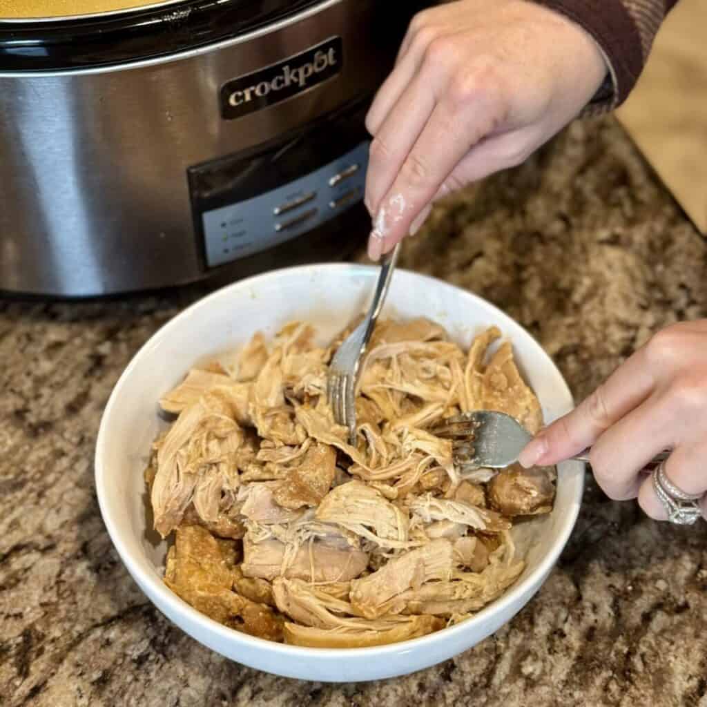 Shredding chicken in an bowl.