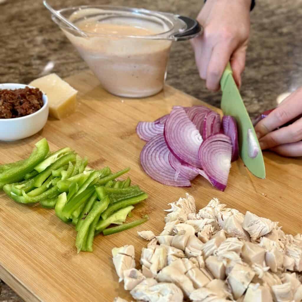 Cutting up vegetables and chicken for a pasta salad.