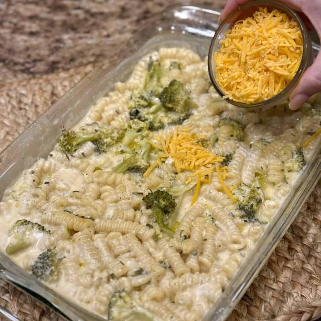 Adding cheese to a dish of broccoli pasta bake.