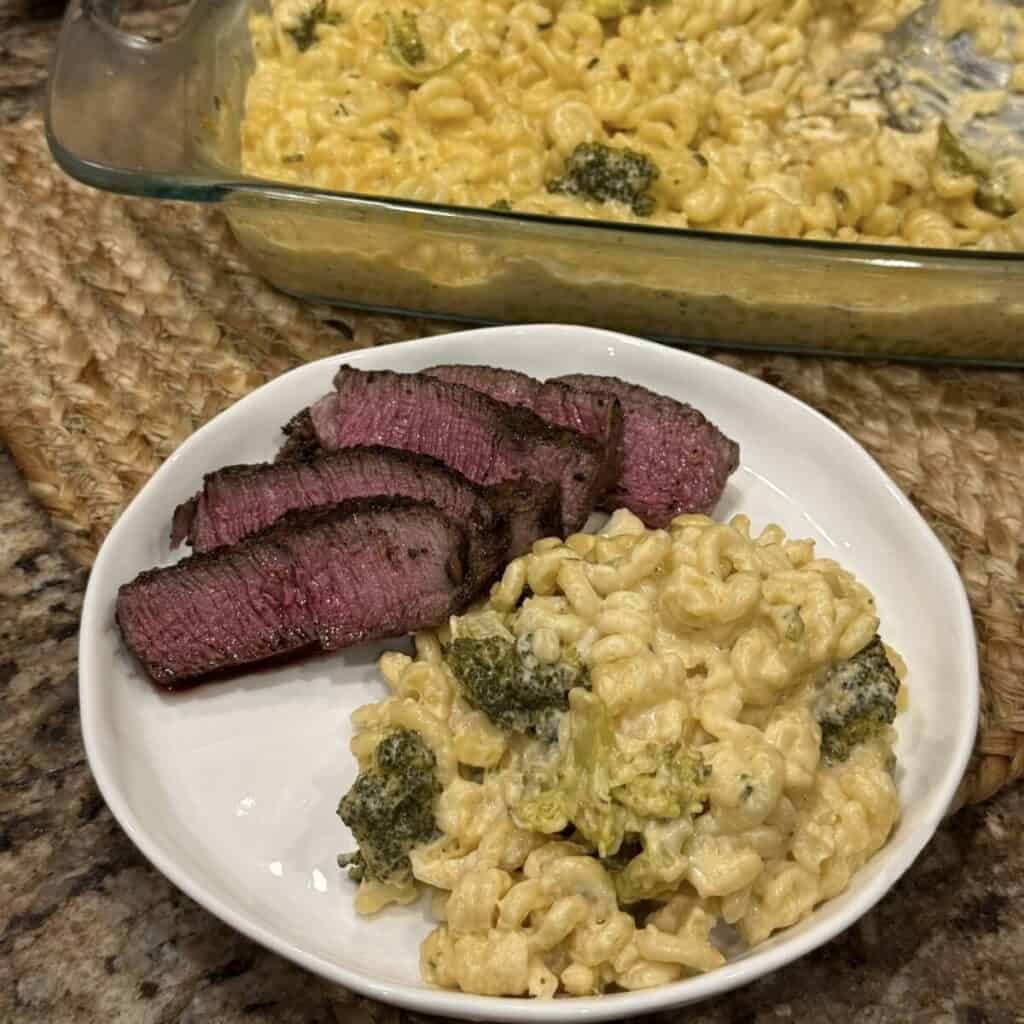 A plate of broccoli pasta bake and steak.