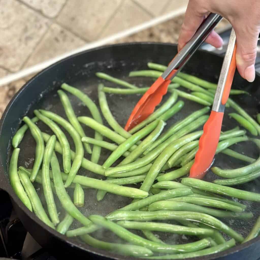 Boiling green beans in a skillet.