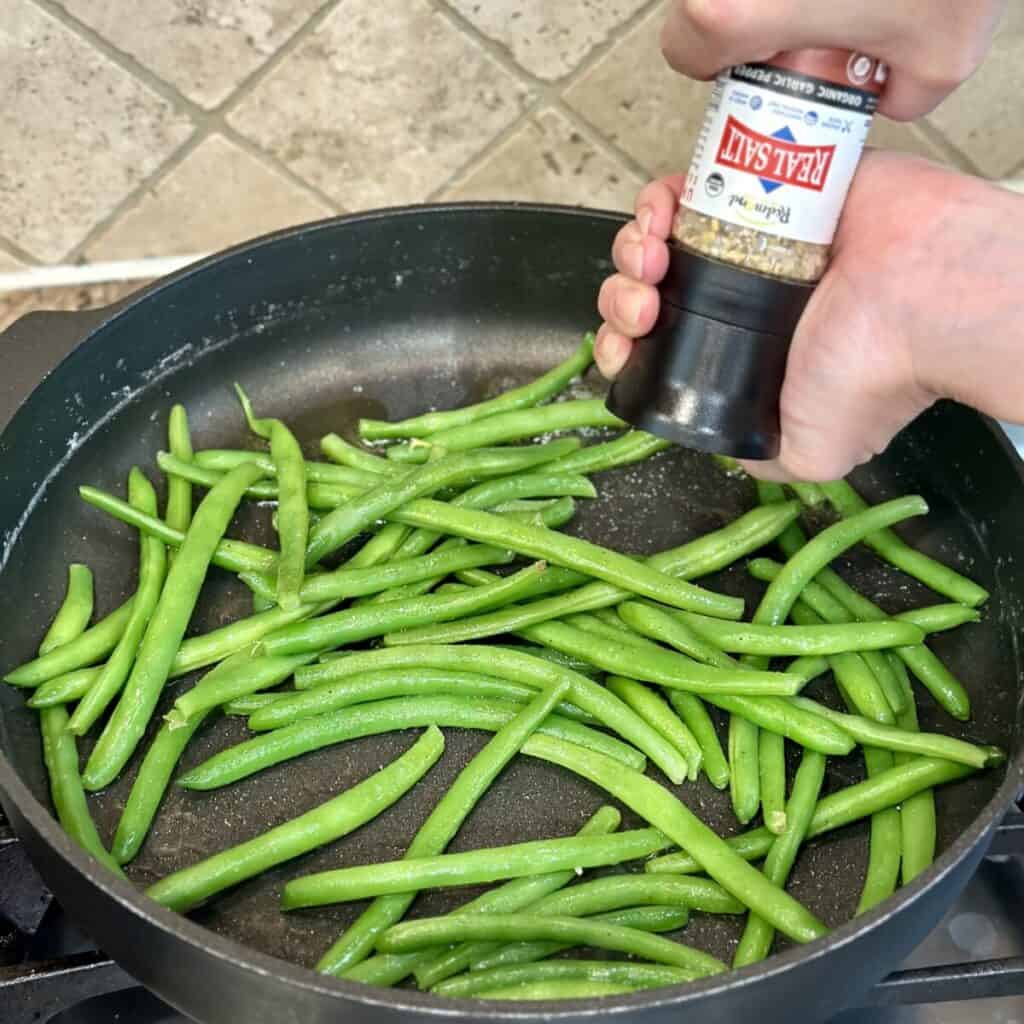 Seasoning green beans with garlic pepper salt.