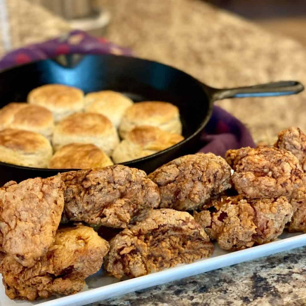 Fried chicken on a platter and biscuits.