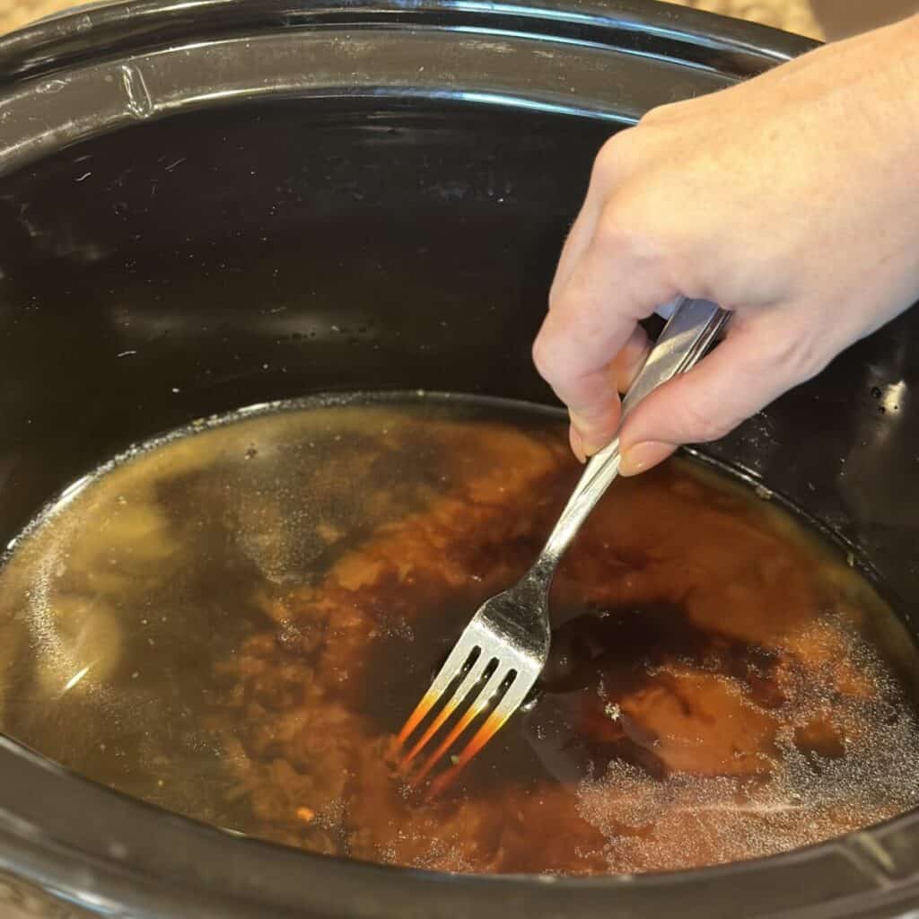 Whisking together sauce in a slow cooker for brisket.