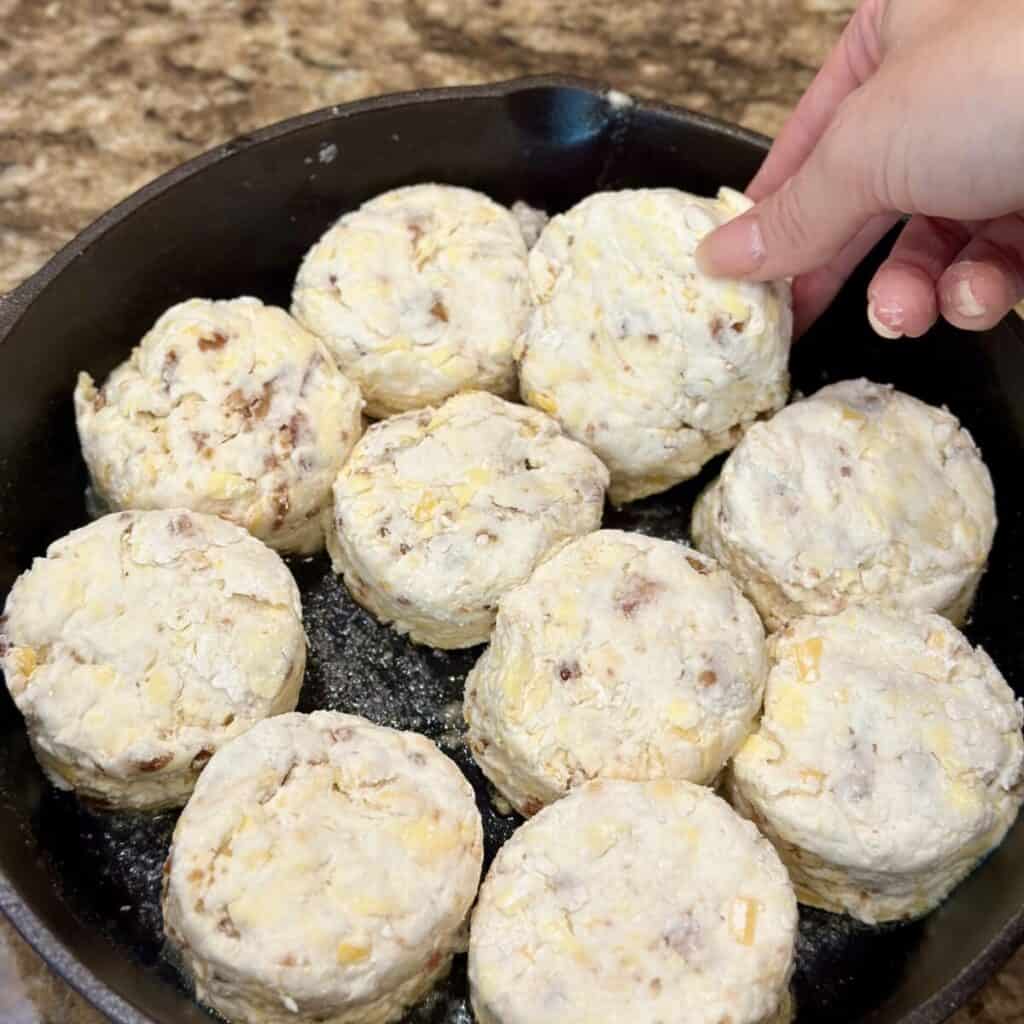 Placing biscuit rounds in a cast iron skillet.