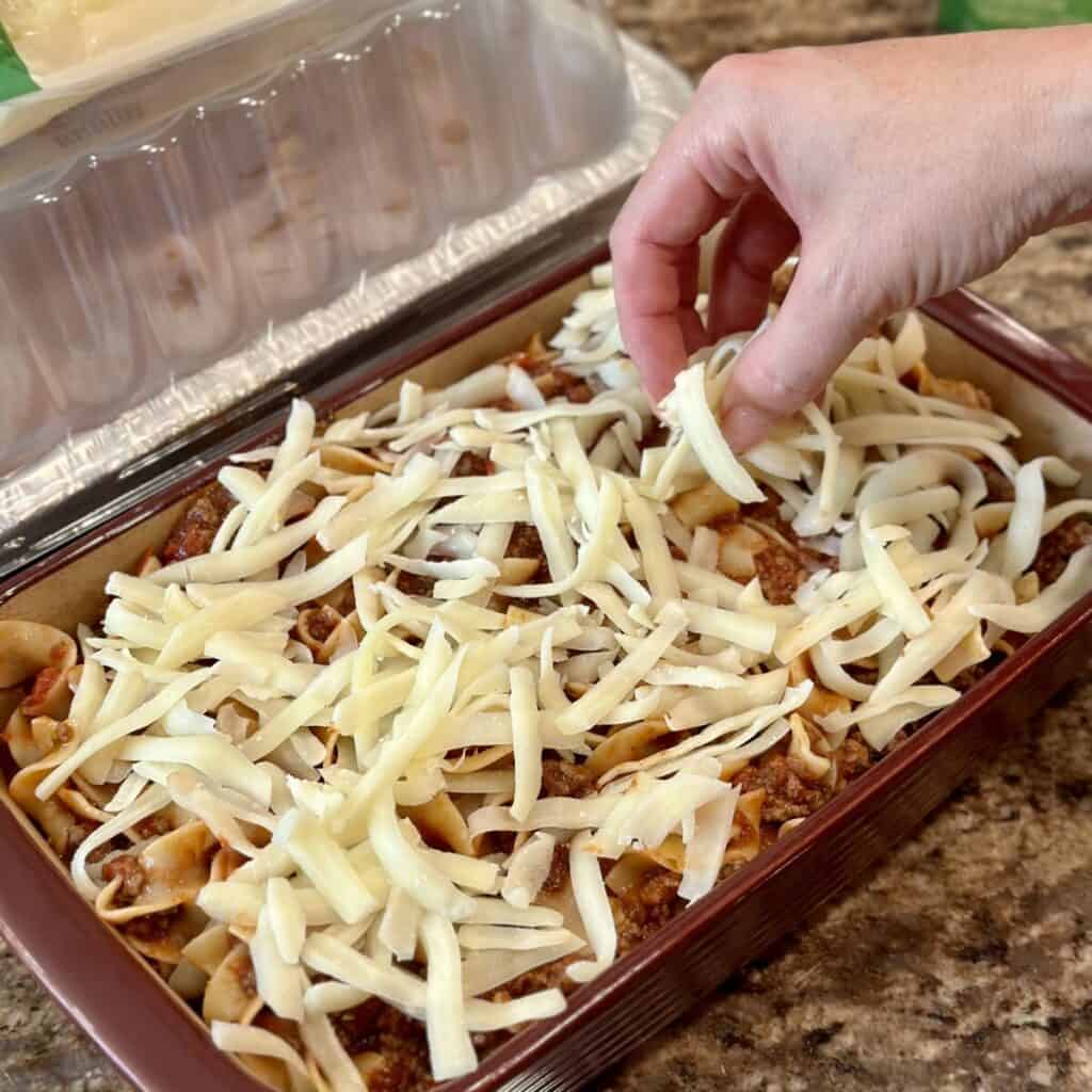 Adding mozzarella cheese to the top of lasagna.