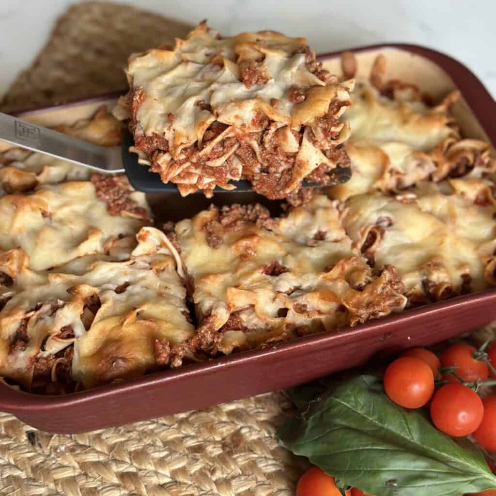 A square serving of lasagna on a spatula.