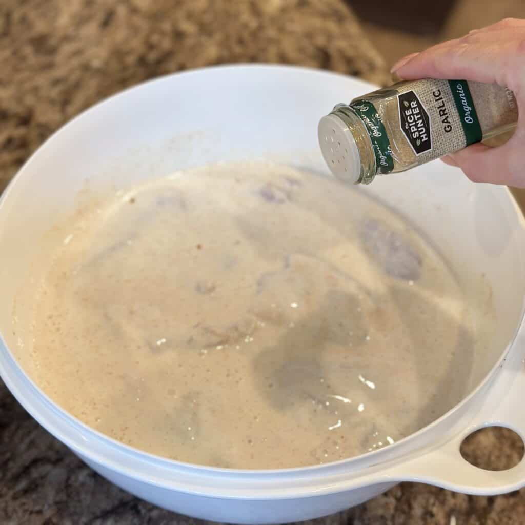 Brining chicken in a bowl with buttermilk.