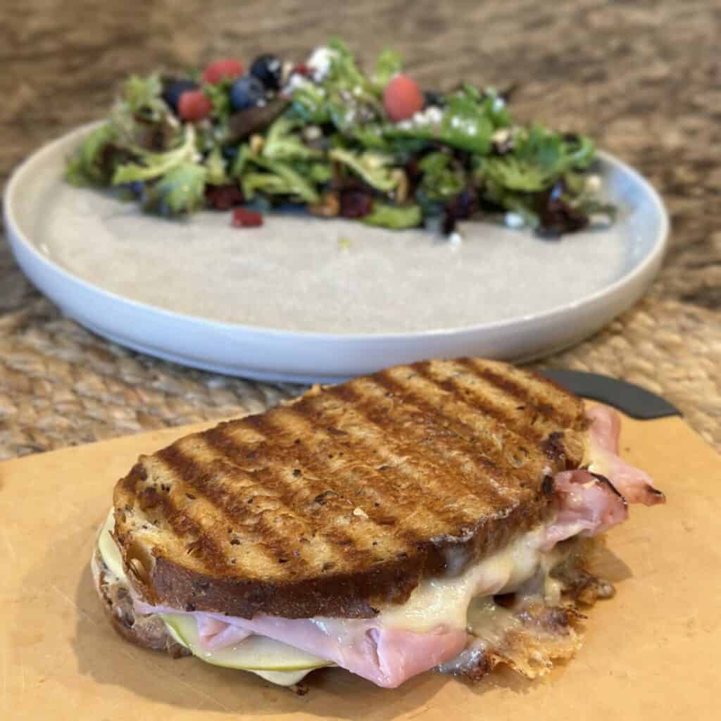 A ham and cheese panini on a cutting board.