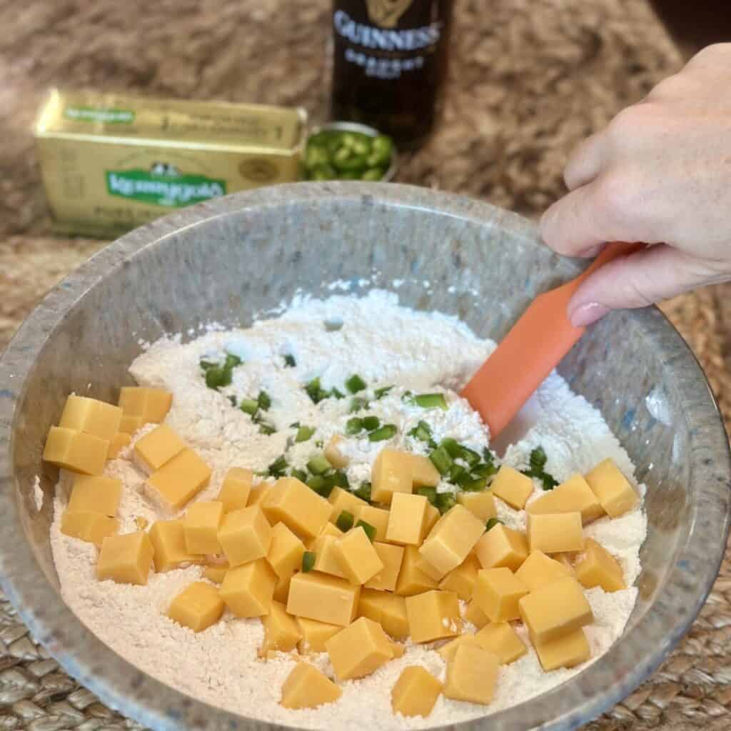 Adding jalapeño and cheese to a beer bread batter.