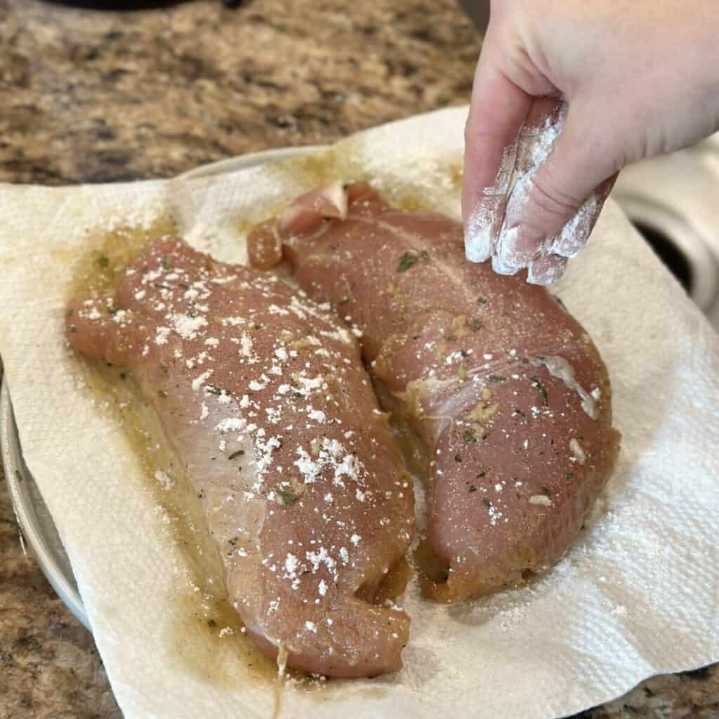 Sprinkling turkey tenderloins with flour.