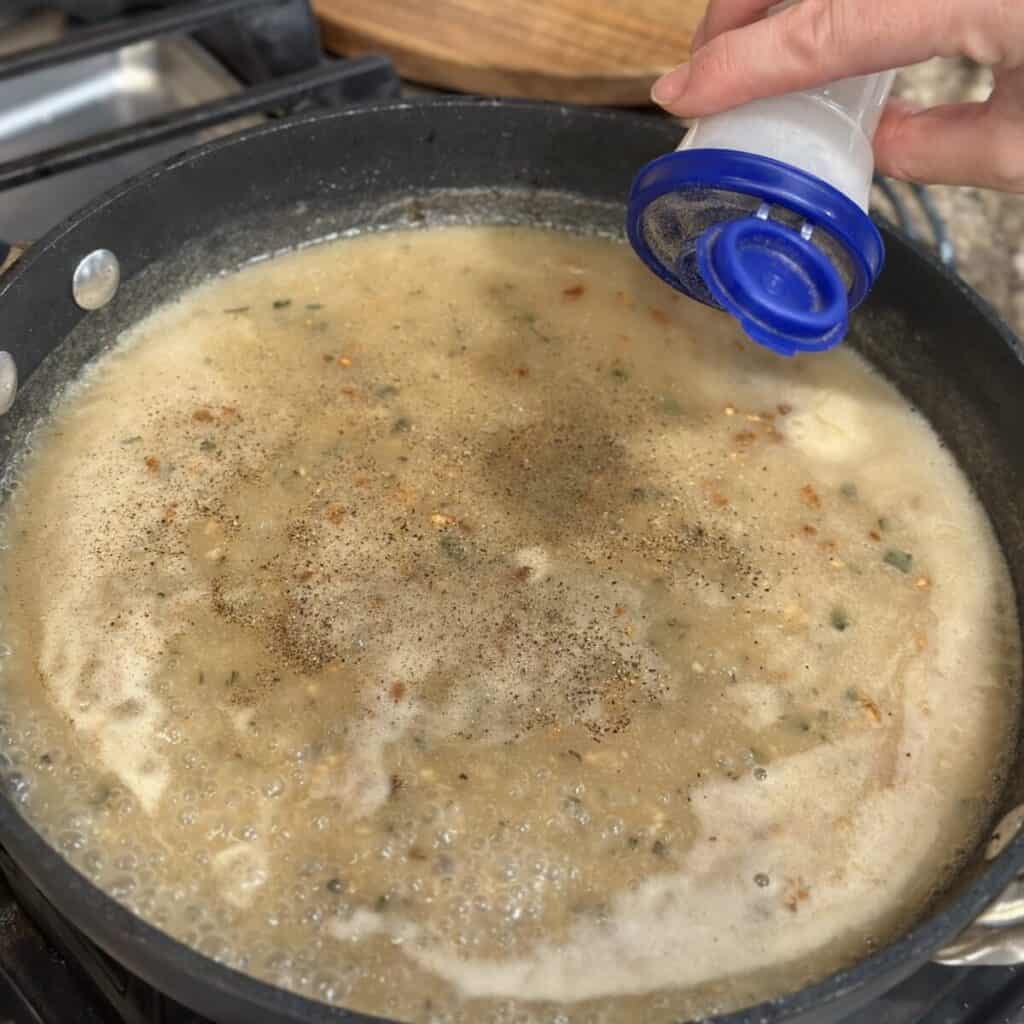 Seasoning gravy in a skillet.