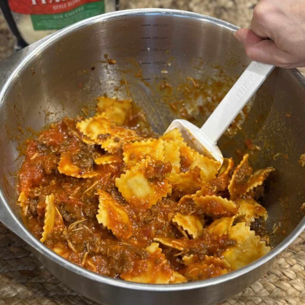 Mixing the ingredients for a baked ravioli recipe in a bowl.