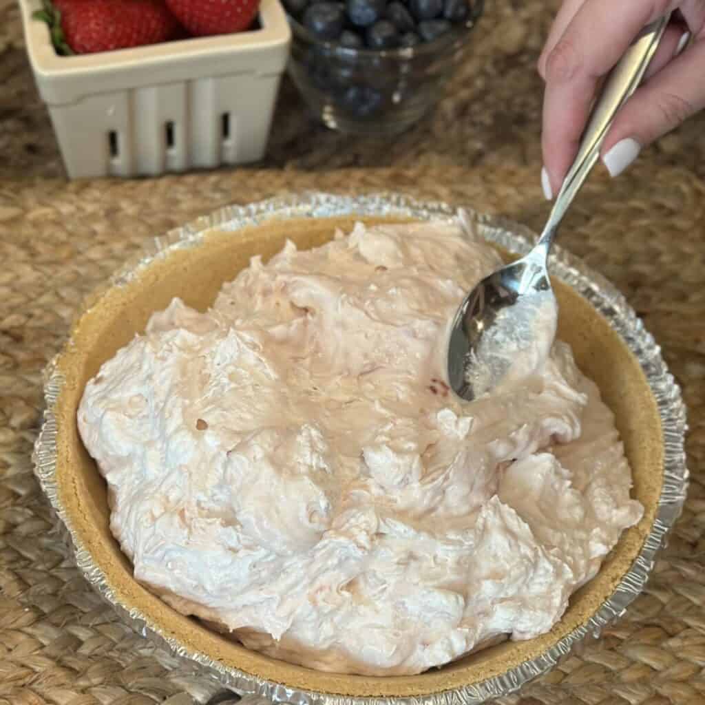 Spreading a pie filling in a graham cracker crust.