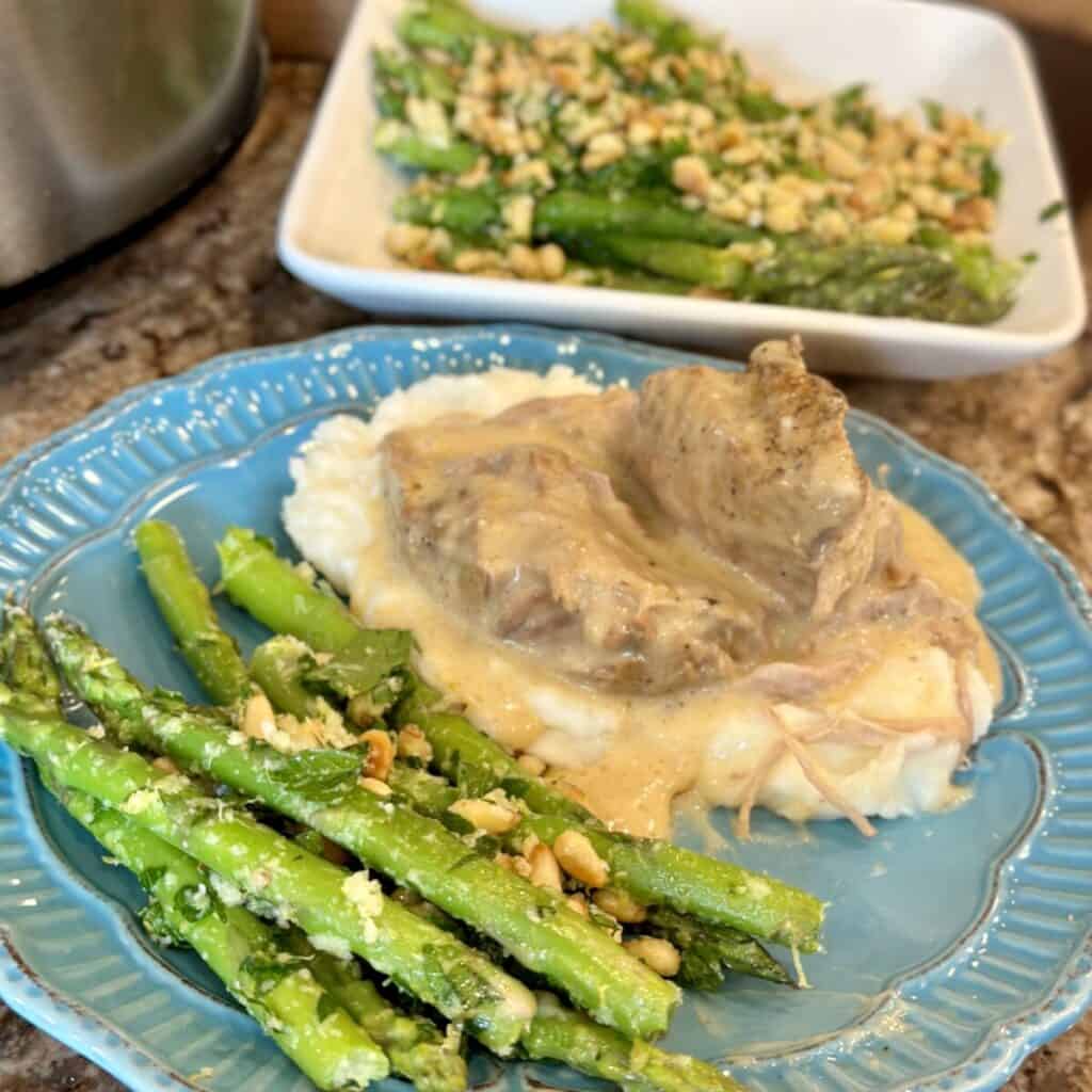 A serving of gremolata asparagus on a plate with ribs.