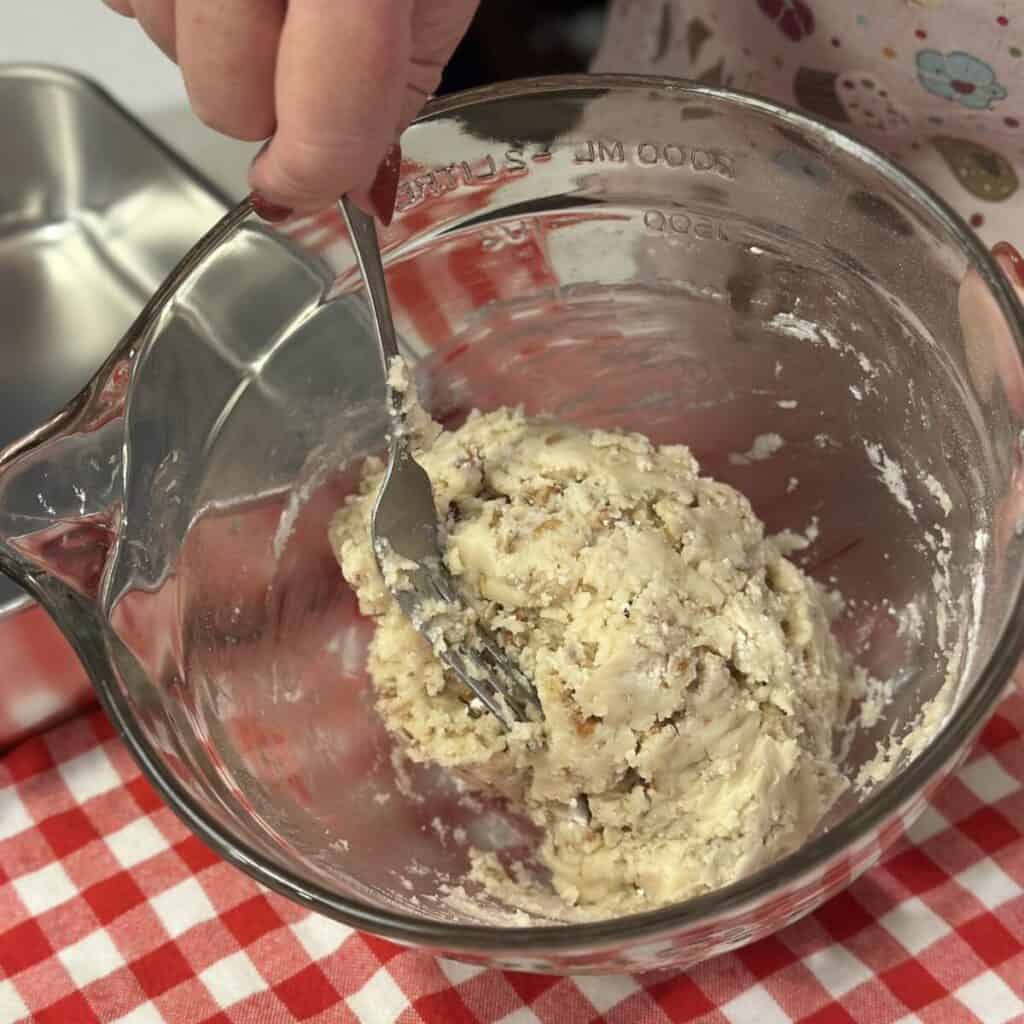 Mixing together the ingredients for a shortbread crust in a bowl.