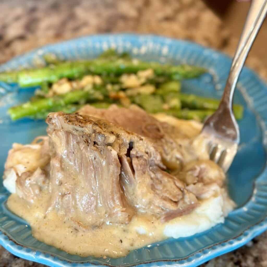 A pork roast with gravy on mashed potatoes.
