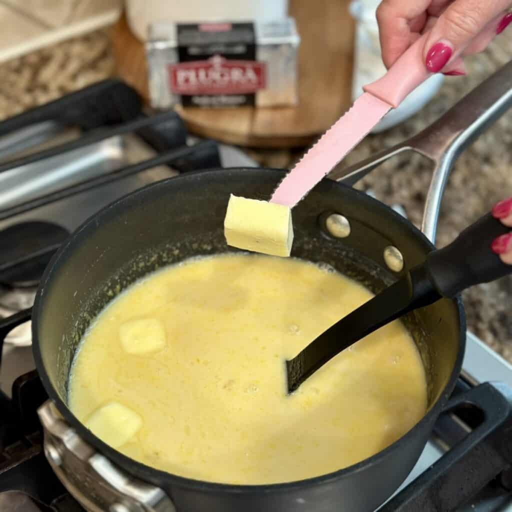 Adding butter to a skillet making pudding.