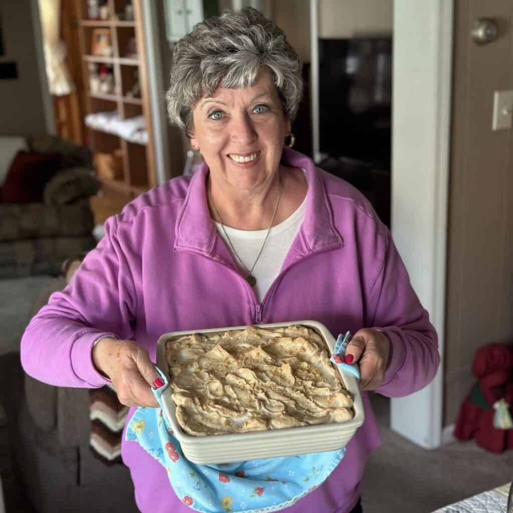 Phyllis holding a baking dish of baked banana pudding.