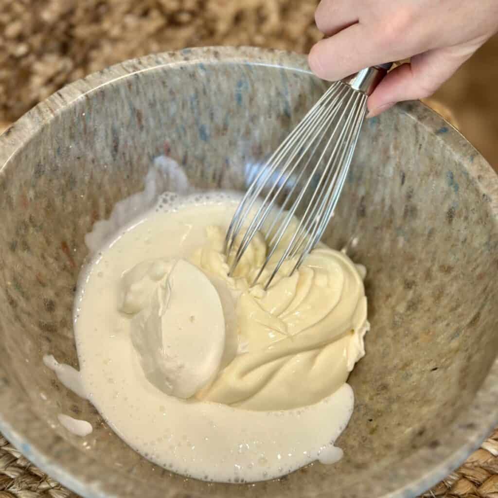 Whisking mayo, buttermilk and sour cream in a bowl.