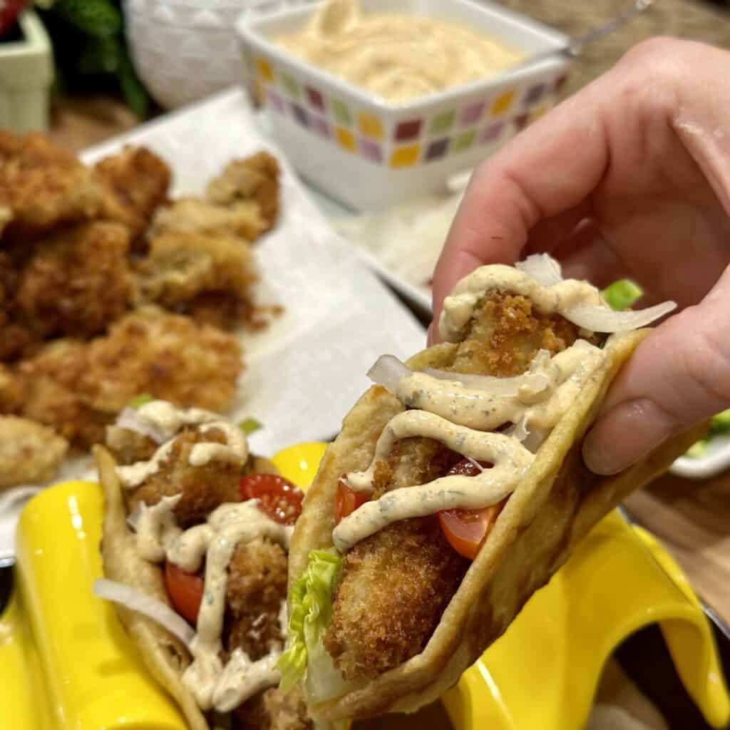 Holding a fried chicken taco.