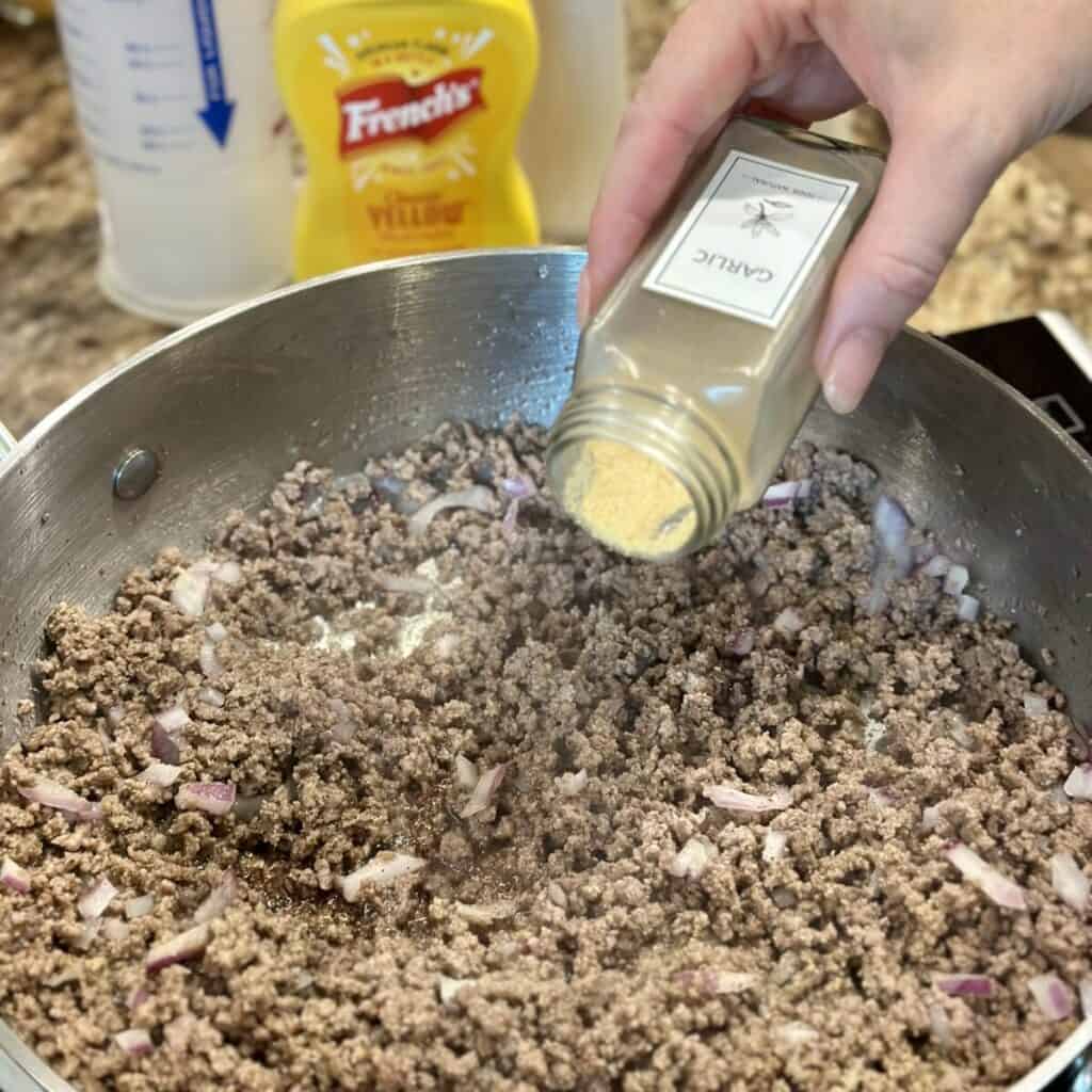 Seasoning ground beef in a skillet.