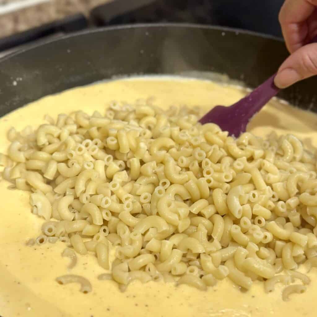 Folding macaroni noodles into a cheese sauce.