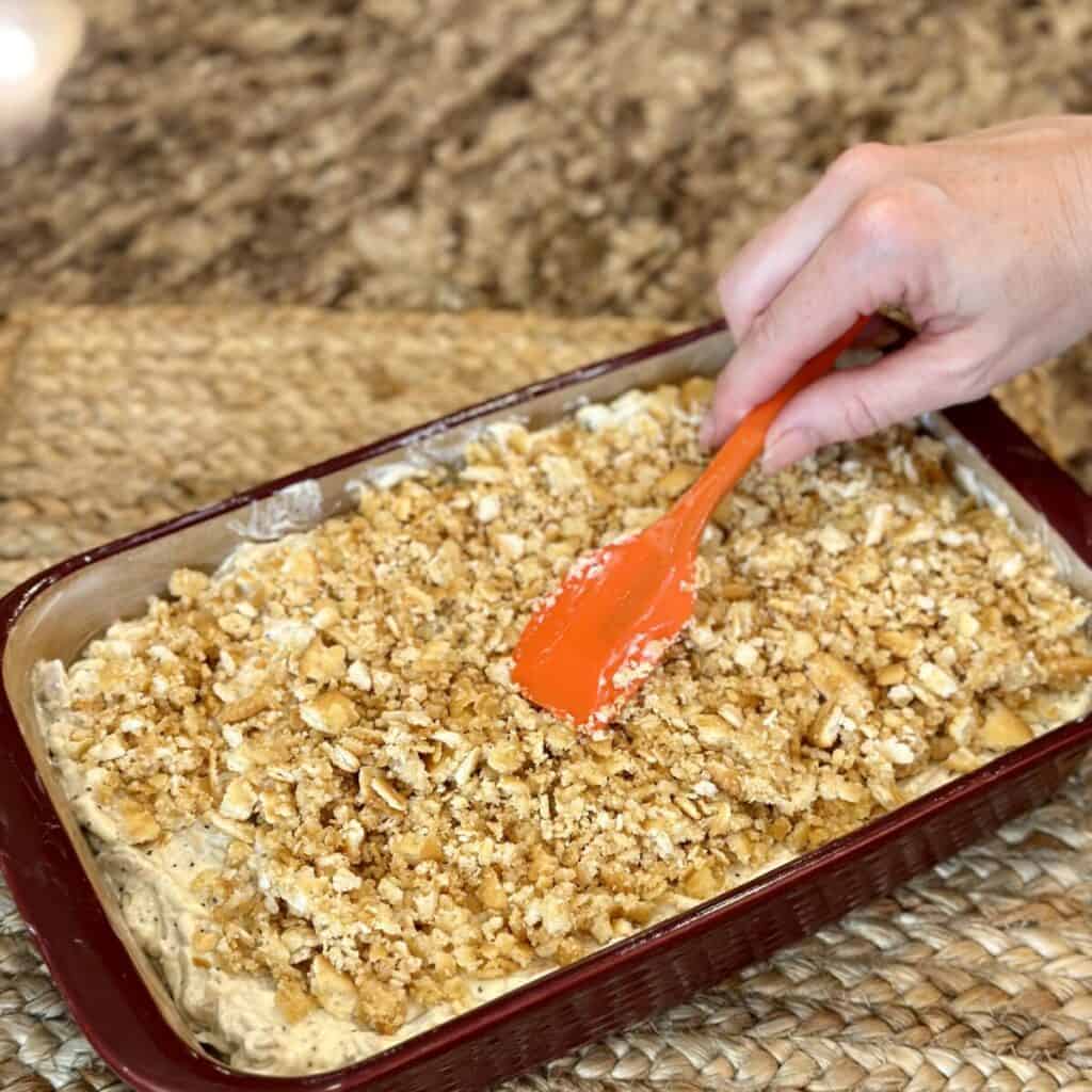 Spreading cracker crumbs on top of a casserole.