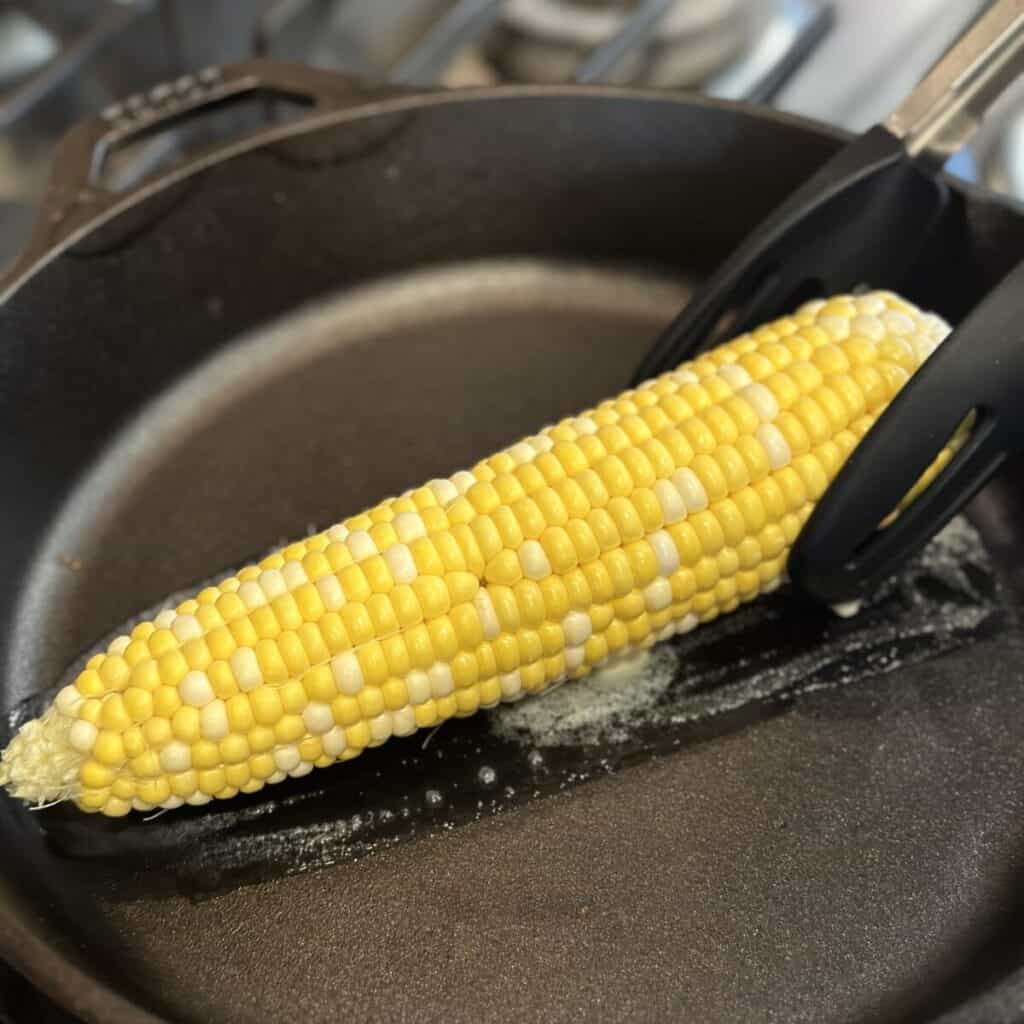 Searing a corn cob in a skillet.