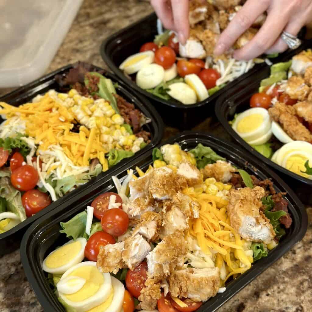 Adding chicken to the top of a salad.