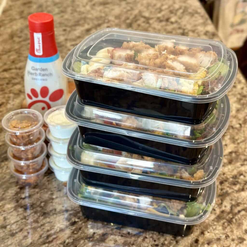 A stack of ready to go salad containers with Cobb salad inside.
