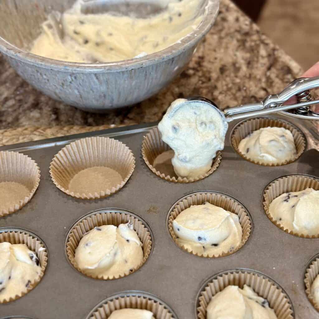 Scooping cupcake batter in a pan.