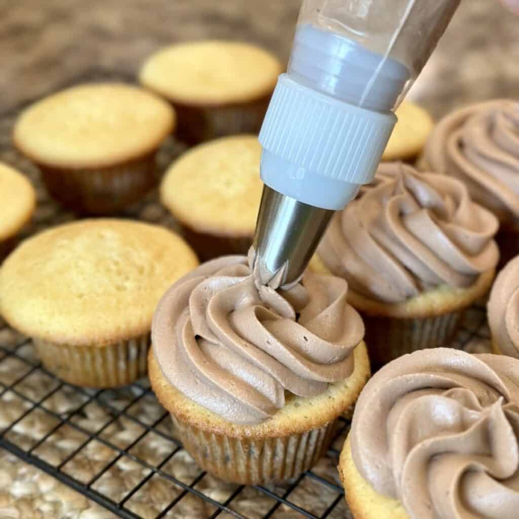 Piping icing on cupcakes.