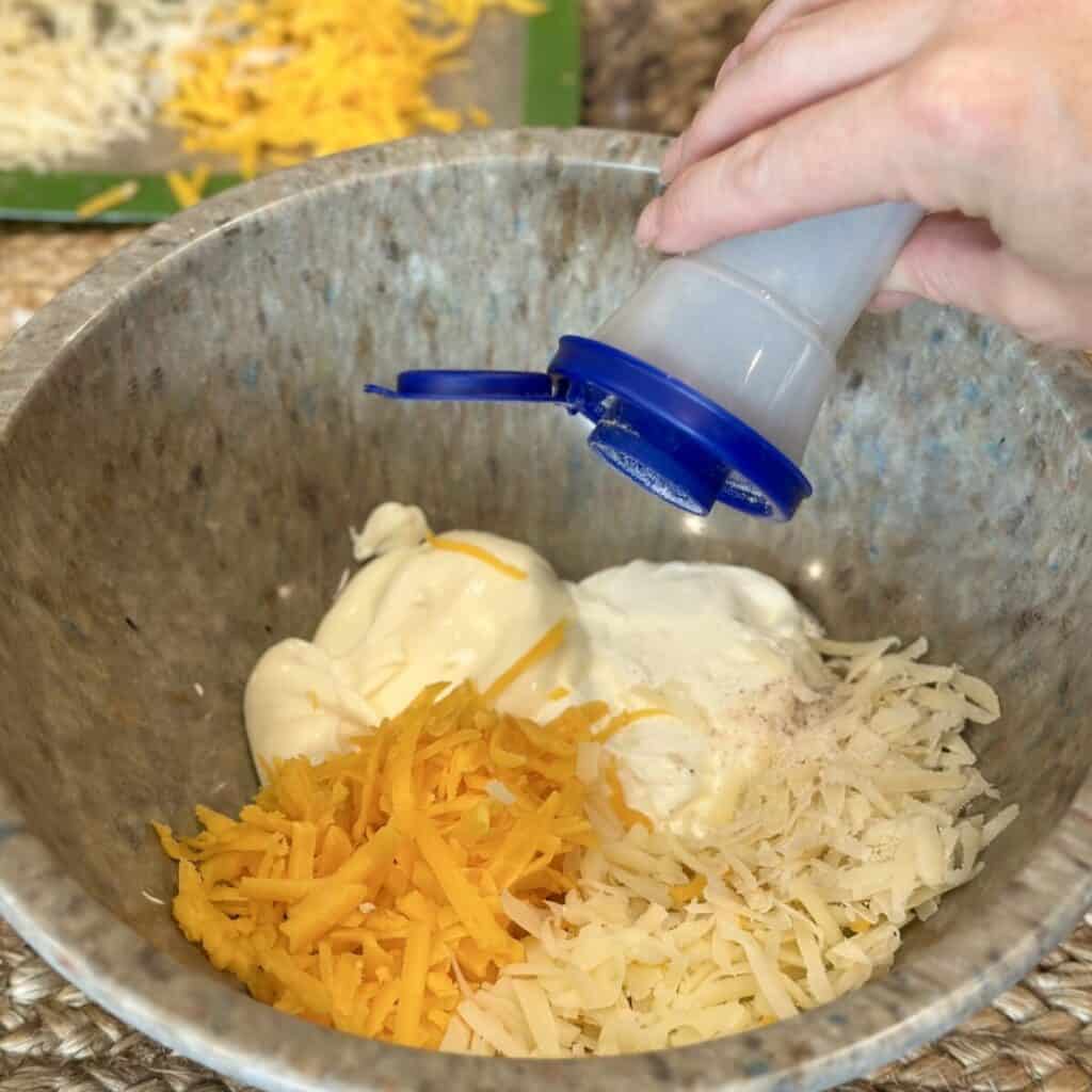 Adding the ingredients for the filling of a squash casserole in a bowl.