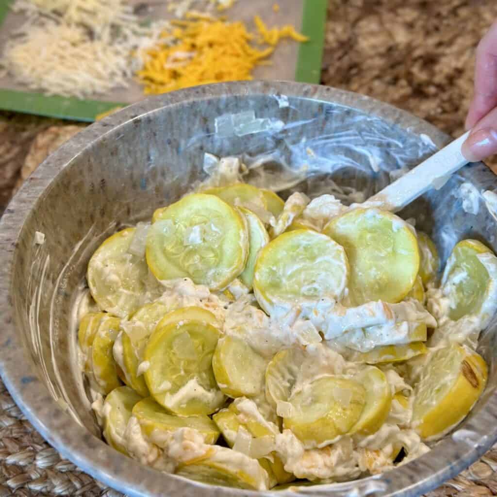 Mixing together the filling for squash casserole in a bowl.