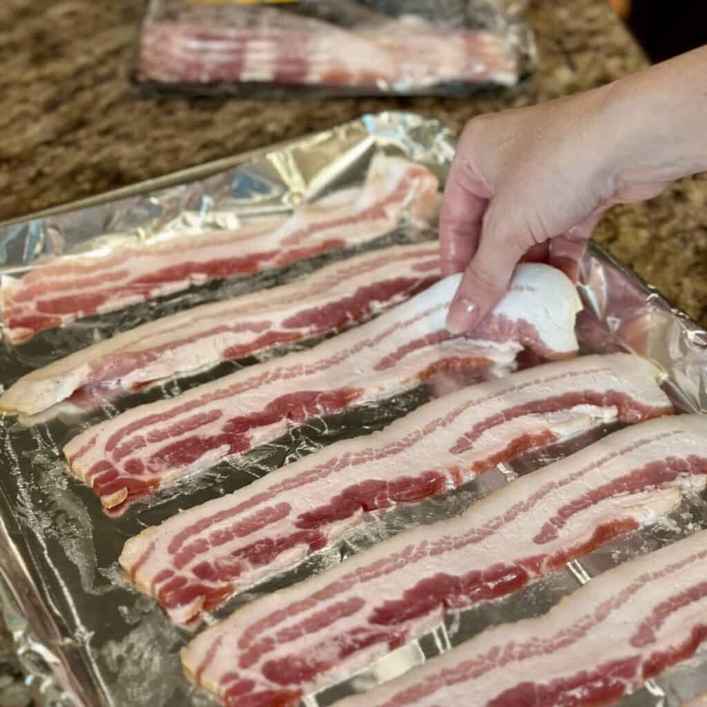 Laying bacon on a sheet pan.