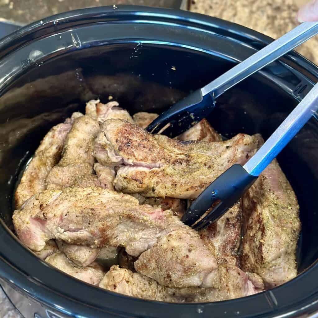 Adding country style ribs to a crockpot.