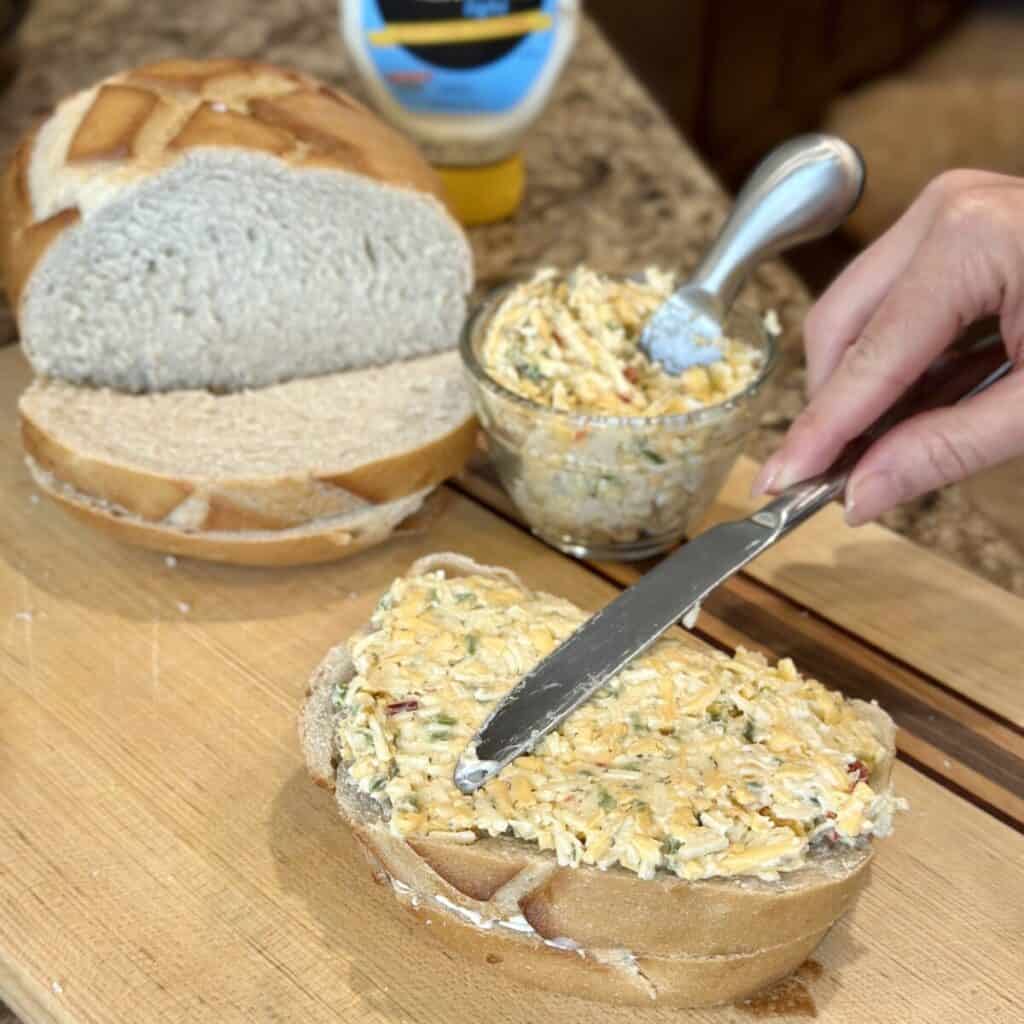 Spreading pimento cheese on bread.